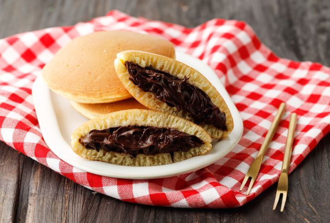 Fresh dorayaki pancakes filled with chocolate from Japan served on checkered napkin with cutlery