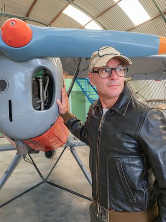 Confident pilot beside retro plane in hangar