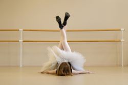 Ballerina in shoes and tutu, performing floor pose