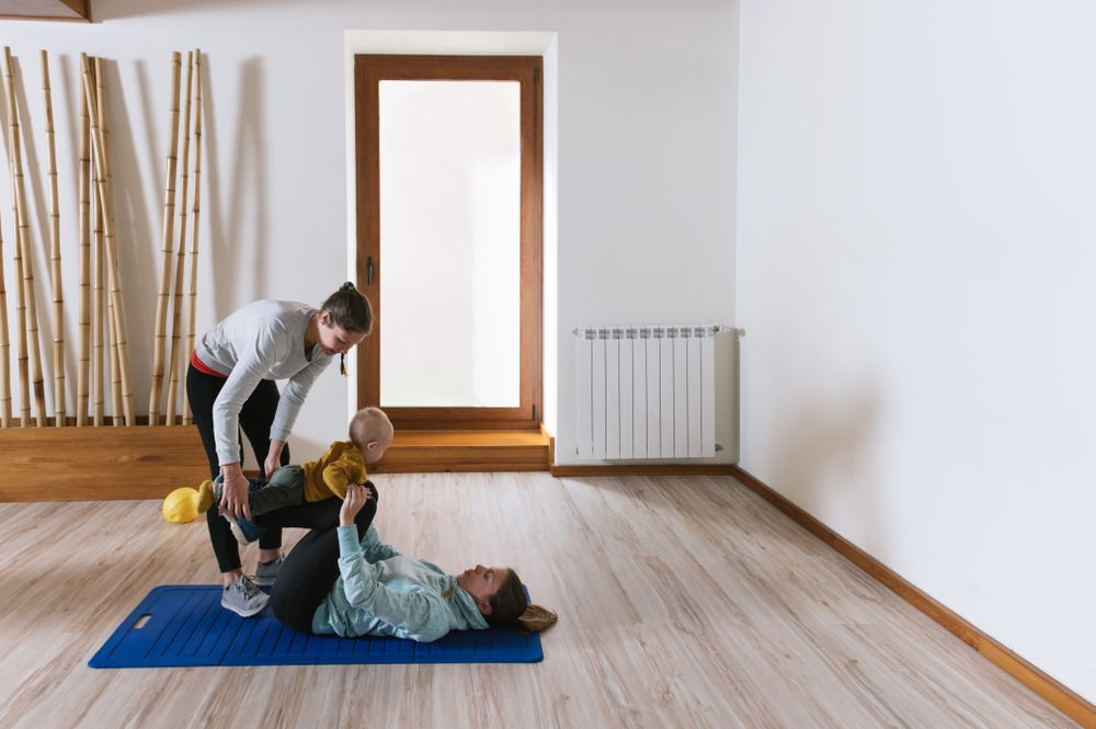 Fitness instructor helping mother with push ups