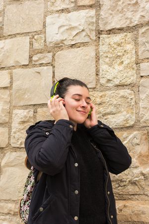 Satisfied young woman smiling while listening to music in earphones