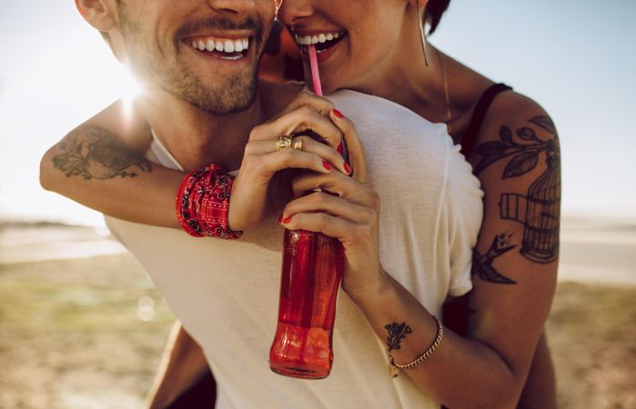 Young romantic couple having great summer holidays holding soda bottle