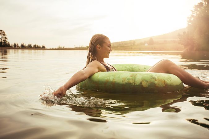 Side portrait of happy young woman in lake on inflatable ring