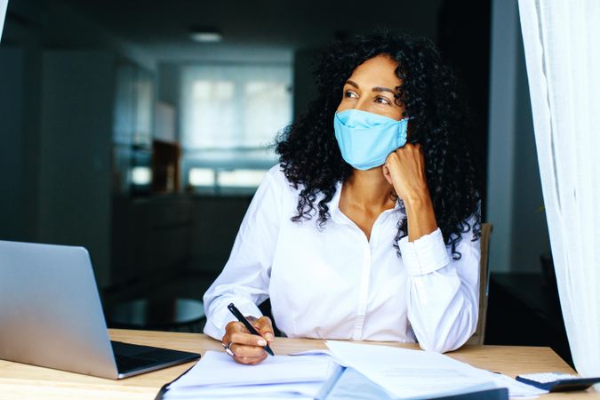 Calm woman wearing a facemask while working on documents