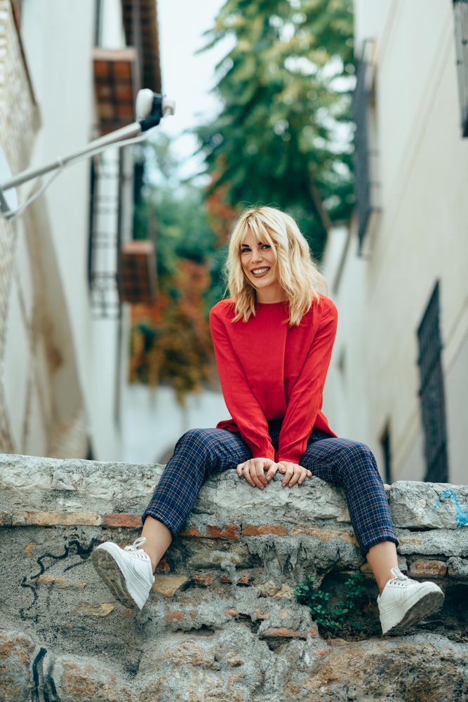 Content blond woman sitting on stone wall