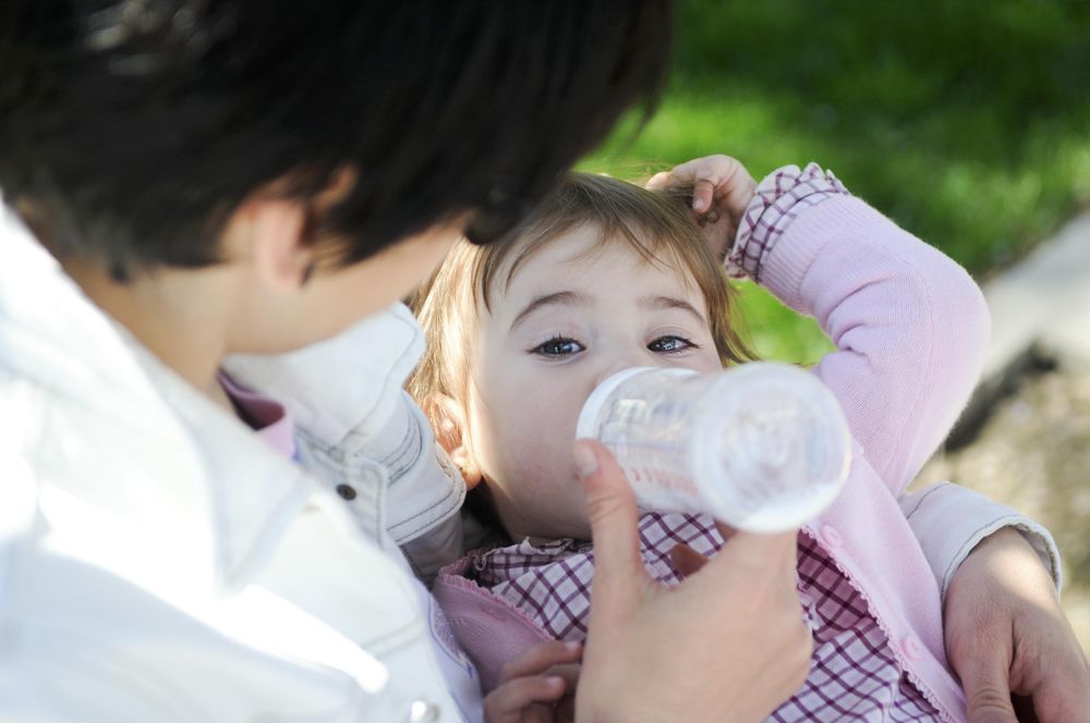 Mother feeding daughter from bottle