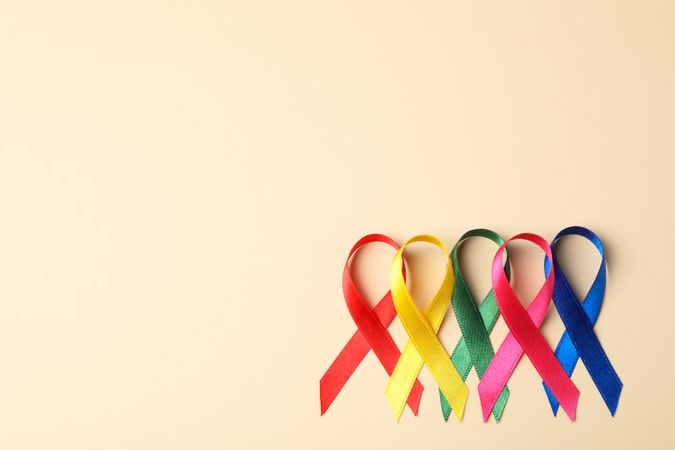 Flat lay composition with awareness ribbons on color background, space for text.