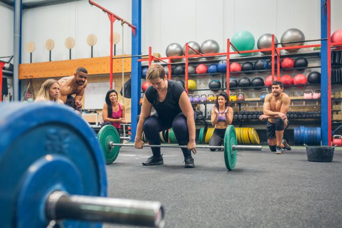 Woman ready to do weightlifting while her gym mates cheering her on