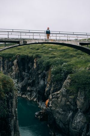 Man on bridge over rugged terrain