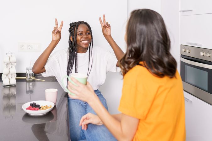 Two women talking with hand gestures over coffee in the kitchen