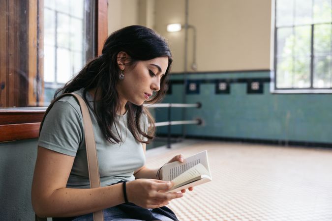 Woman reading a book at train station
