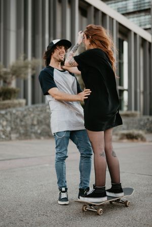 Man helping girlfriend to skate on road