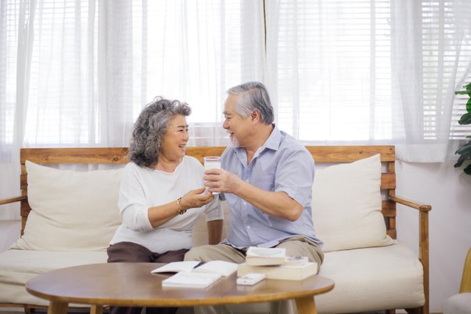 Older woman handing glass of milk to husband in living room
