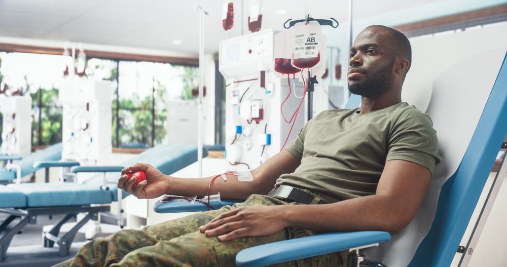 Black Male Army Soldier Donating Blood For Injured Comrades In Military Hospital.