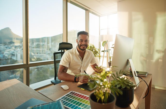 Attractive male designer sitting at his desk and smiling