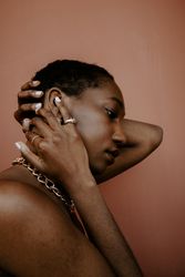 Side view of woman wearing gold jewelry touching face