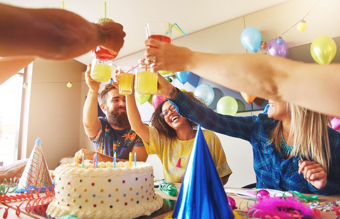 Friends raising their cocktail drinks at a birthday party toasting the birthday girl