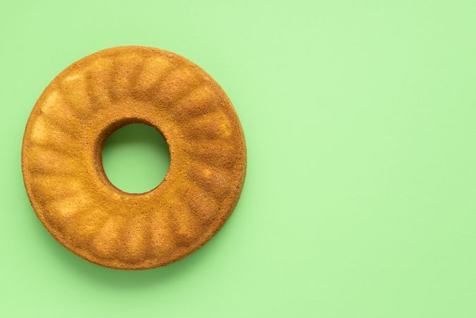 Overhead of whole cornmeal cake on mint background