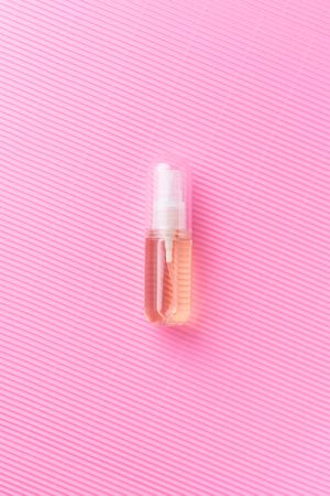 Small pink perfume over pink background