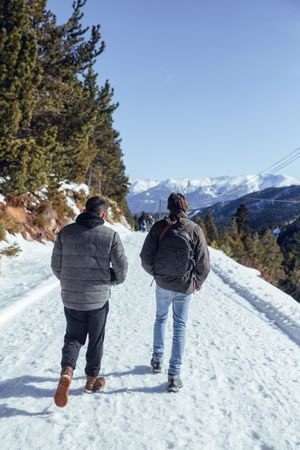 Men walking on road between hills with trees in winter