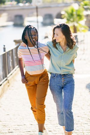 Female friends in casual clothing walking up cobble stone path