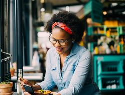 Woman smiling at her phone while eating at a cafe