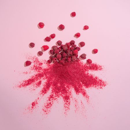 Raspberries with red dust on pink background