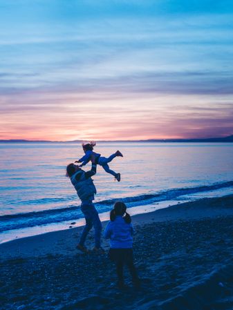 dad rocking kid at the beach