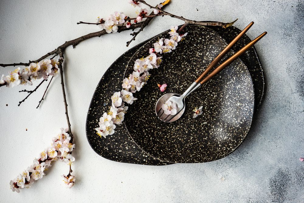 Table setting with delicate apricot blossom around elegant dark tableware