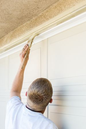 Professional Painter Cutting In With Brush to Paint Garage Door Frame