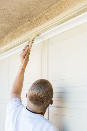 Professional Painter Cutting In With Brush to Paint Garage Door Frame
