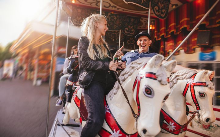 Smiling man and woman on amusement park carousel