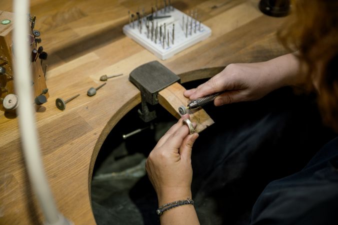 unrecognizable woman grinding ring in jewelry atelier