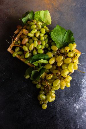Top view of box of delicious fresh green grapes with leaves on counter