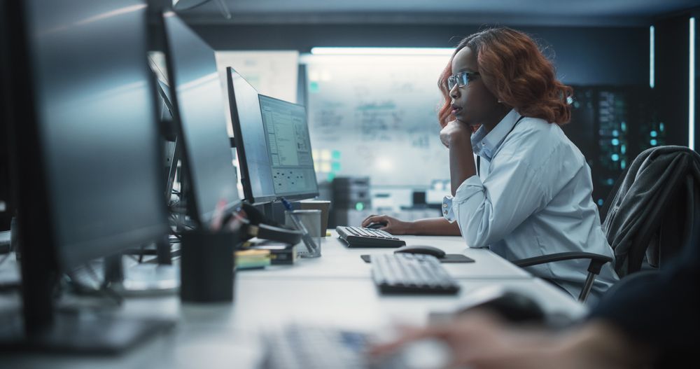 Focused Young Black Female Software Developer Working on Computer Together with Two Creative Male Colleagues.