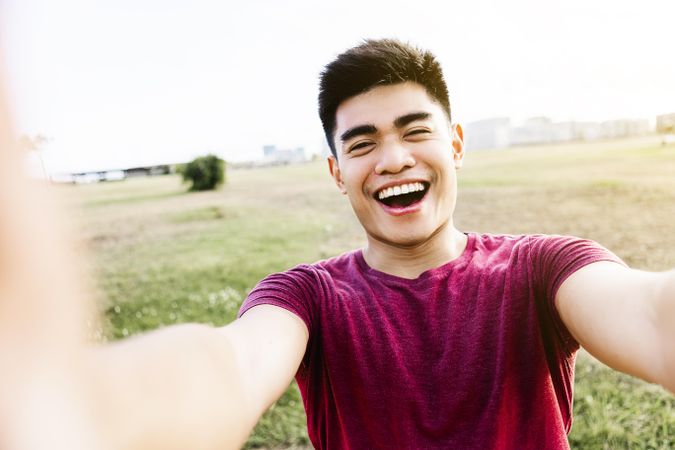 POV of smiling male taking picture of himself in field