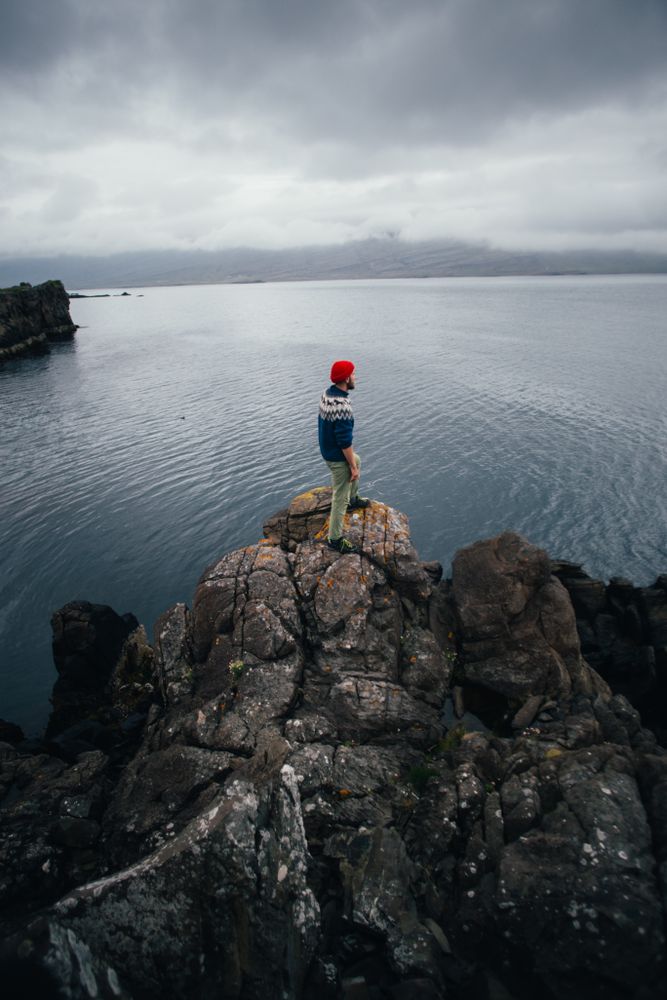 Man standing on edge of cliff on overcast day, portrait