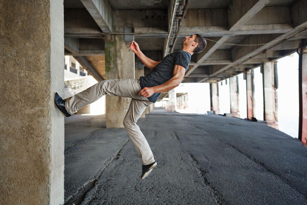 Male running up wall in industrial cement space
