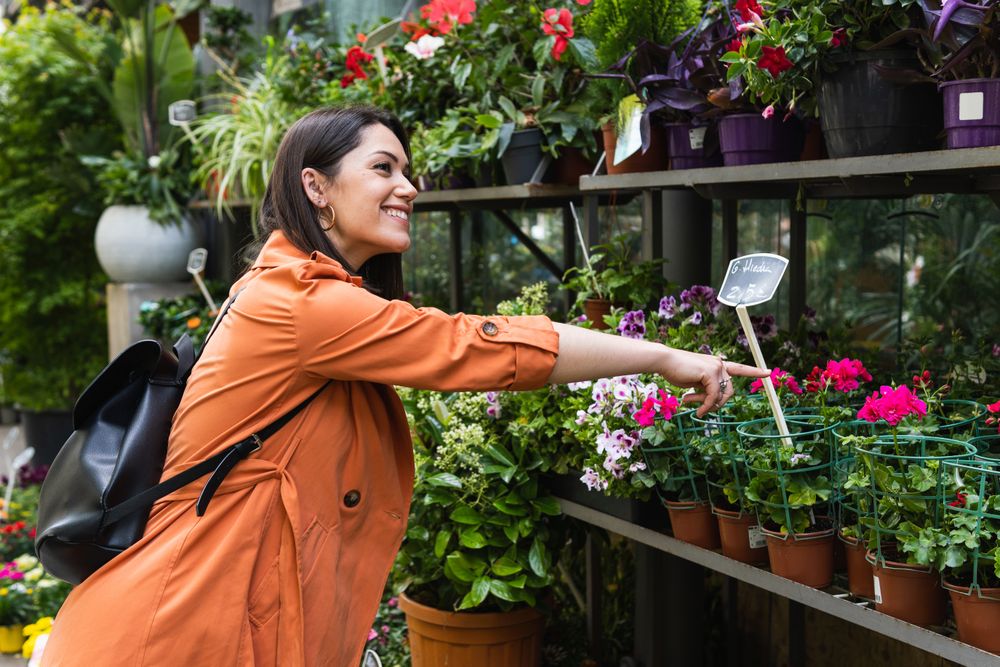 Cheerful woman choosing flowers in garden center