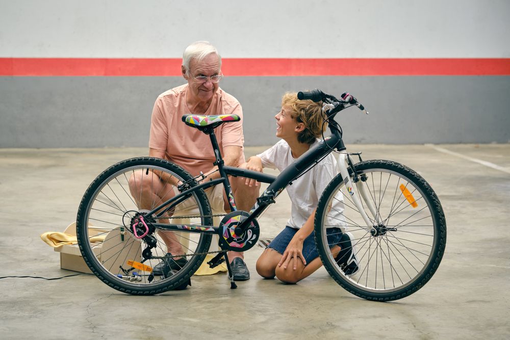 Smiling grandfather talking to grandson while fixing bicycle