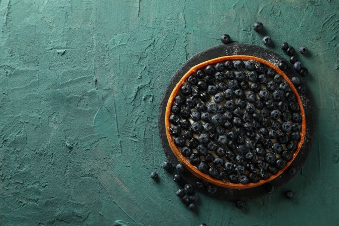 Tray with blueberry pie on green background