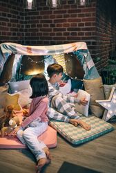 Children preparing tent with chairs and bed sheets