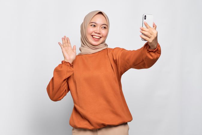 Waving Muslim woman talking on video call