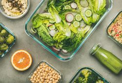 Variety of vegetable dishes in glass containers with bottle of dressing