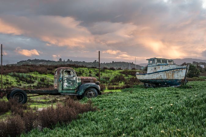 Old, weathered remains of boat and vintage car in field
