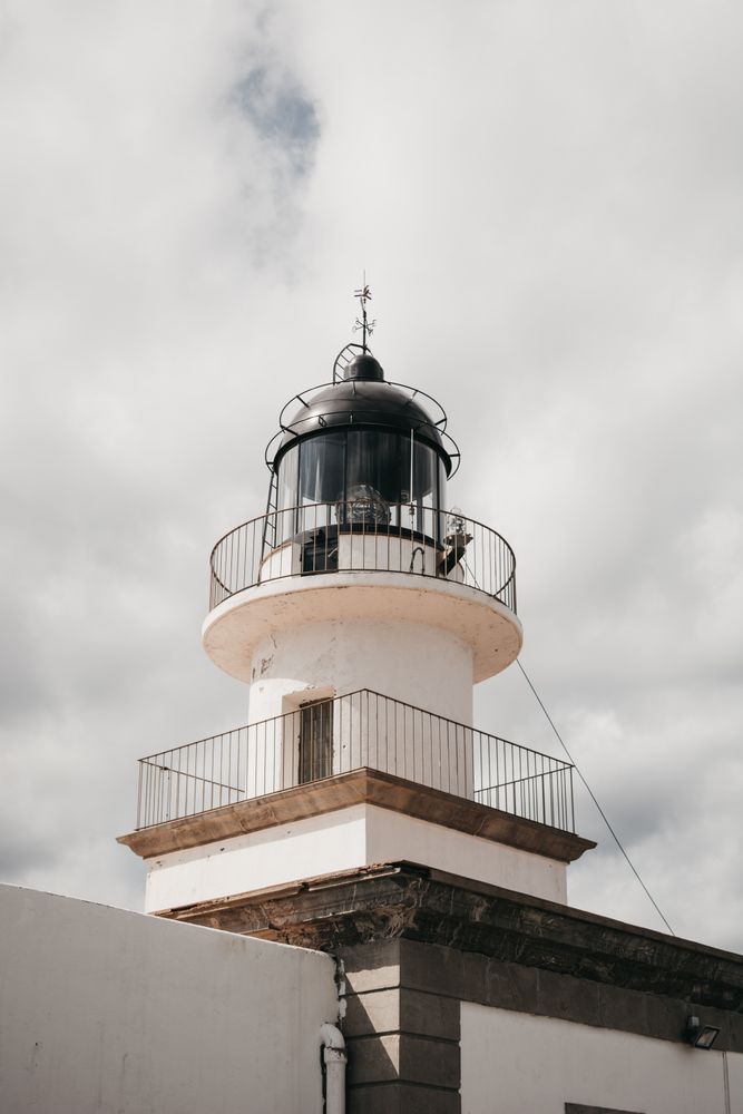 Top of beacon against cloudy sky