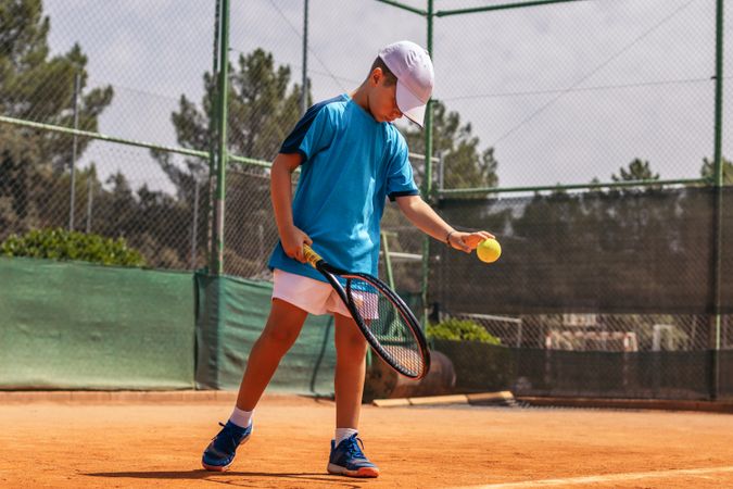 Little boy playing tennis on a dirt court