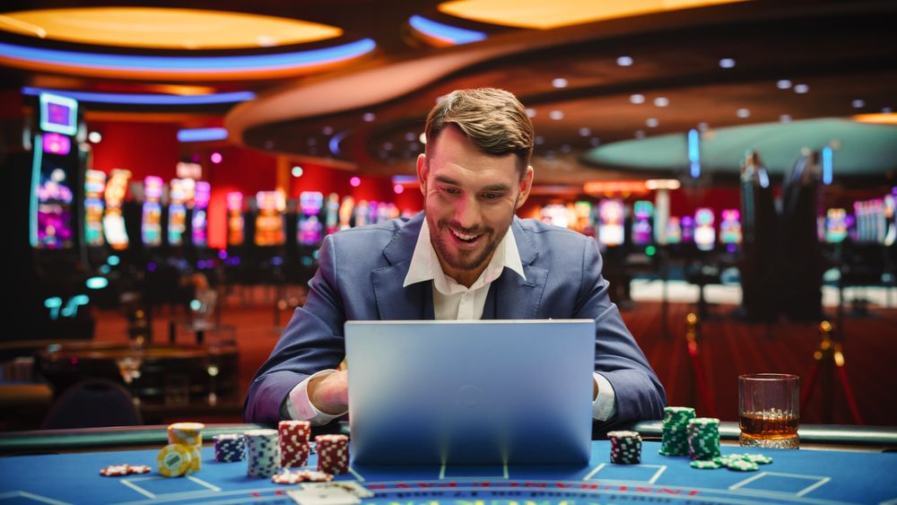 Portrait of a Happy Young Man in a Suit Using a Laptop Computer in Casino.