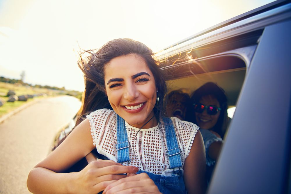 Happy woman leaning out of car window