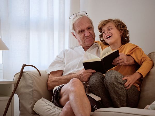Grandfather and grandson spending time together reading book